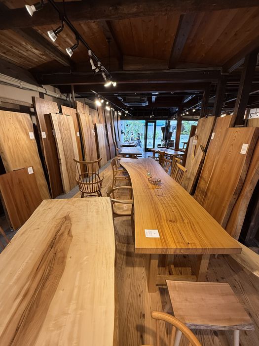 店内に並ぶ一枚板のテーブルと、立てかけられた板