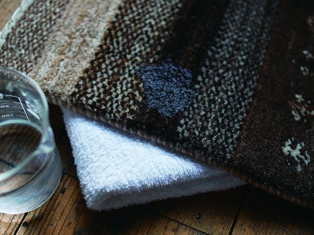 こぼしたところの下にタオルを敷いて、水を含ませたタオルで拭き取るところ