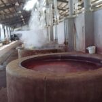 染め工場の丸い大釜。赤く染まった湯から湯気が上がっている