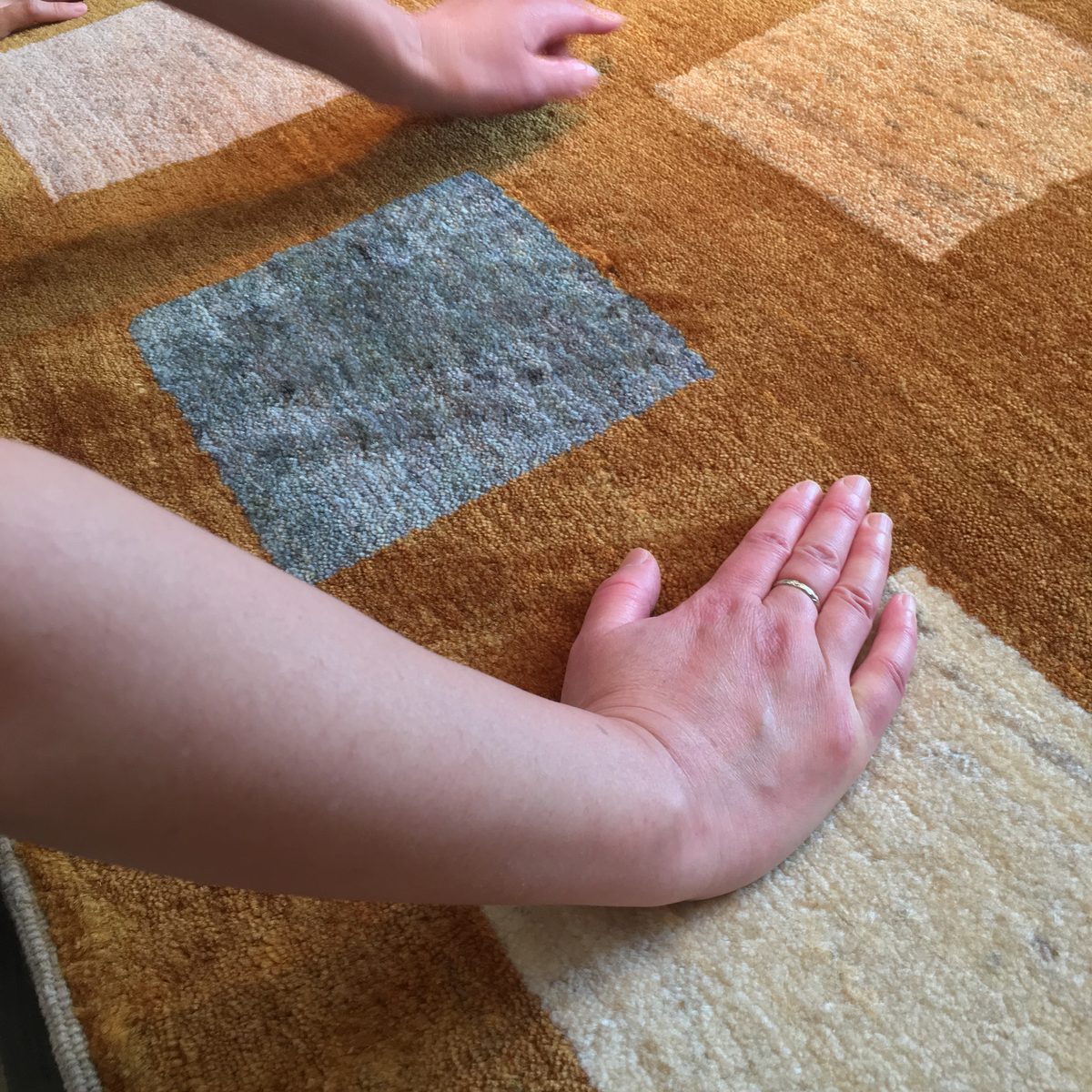 手首の内側から手のひらを、ギャッベの毛並みに当てているところ