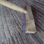 しま模様のギャッベの毛並みにあてた、木の柄のブラシ